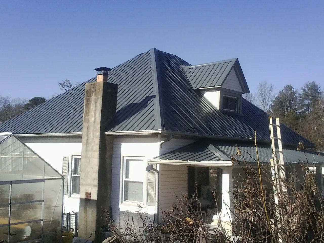 Dark blue standing seam metal roof on a white farmhouse with dormer — Slate & Tile Roof Repair by Roofing Brothers in Shoemakersville