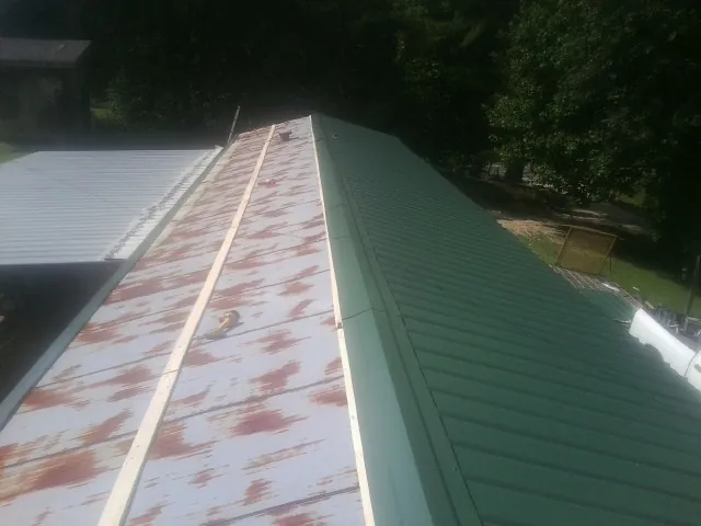 Old rusted panels beside newly installed green metal roofing — Wind Damage Roof Repair by Roofing Brothers in Shoemakersville