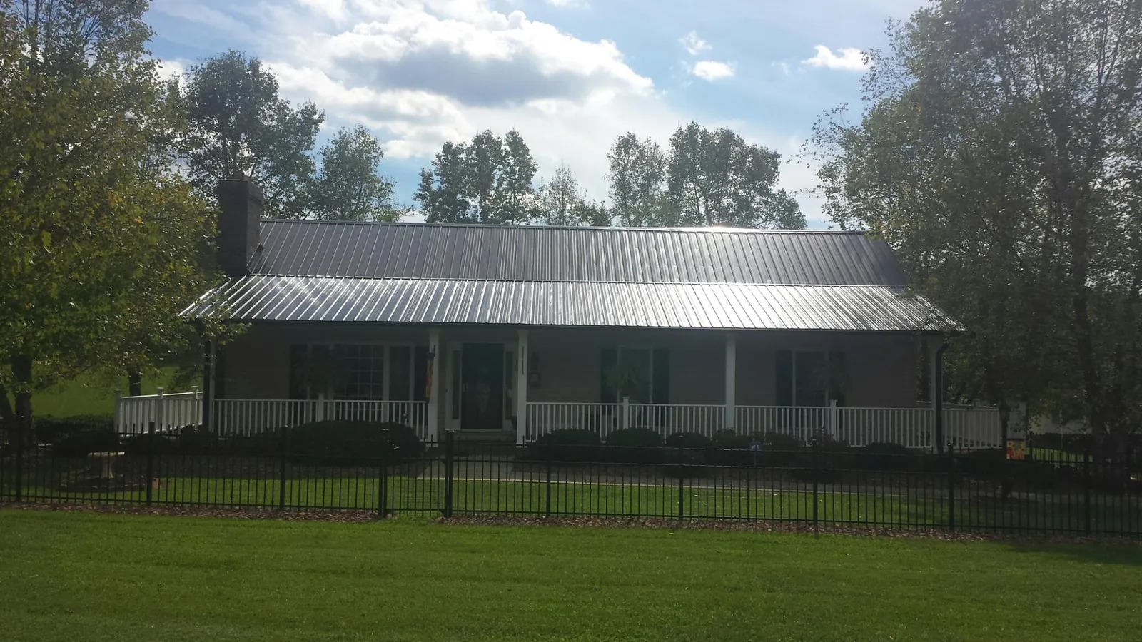 Gray metal roof on a brick ranch with a full width front porch — Gutter Guard Installation work by our crew in Shoemakersville