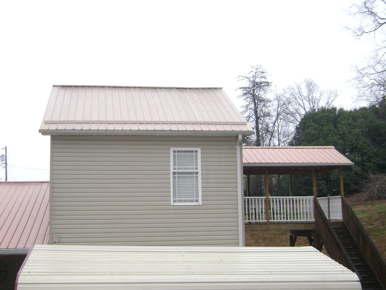 Tan metal roofs on a two story addition and attached porch, from a Roof Replacement job in Shoemakersville