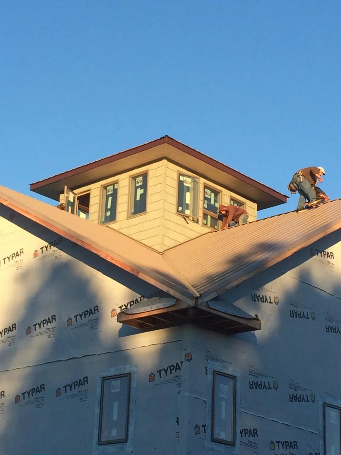 Roofers working around a rooftop cupola on a new metal roof at sunset — Roof Waterproofing in Shoemakersville by Roofing Brothers